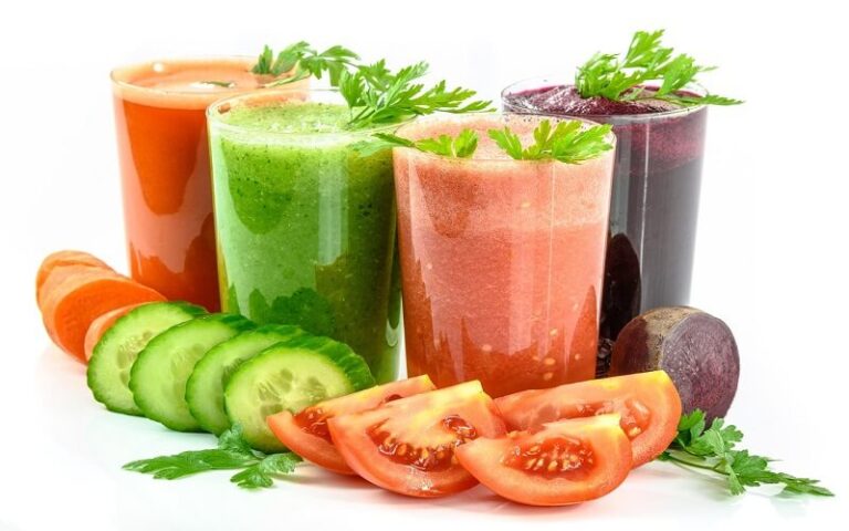 Copo de suco detox de abacaxi, couve e gengibre servido em recipiente transparente."