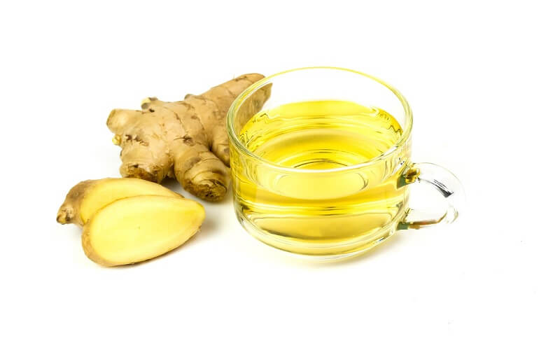 "Chá de gengibre fresco em uma xícara, um anti-inflamatório natural para tratar a garganta inflamada."