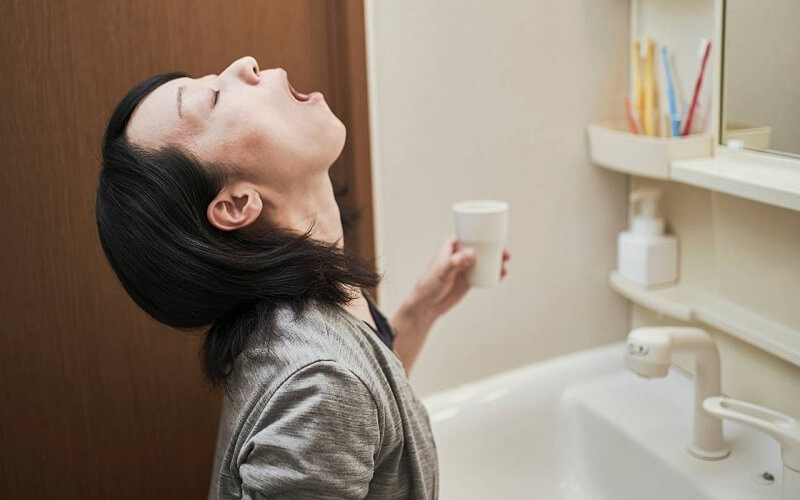 "Preparação de gargarejo com suco de limão e água morna para aliviar a inflamação na garganta."